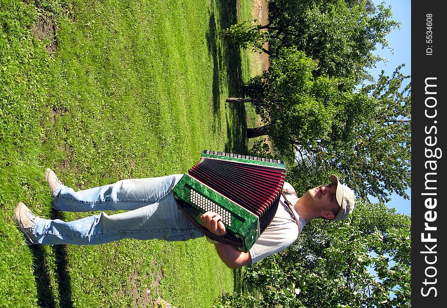 Young man,  playing the accordion in the garden. Young man,  playing the accordion in the garden