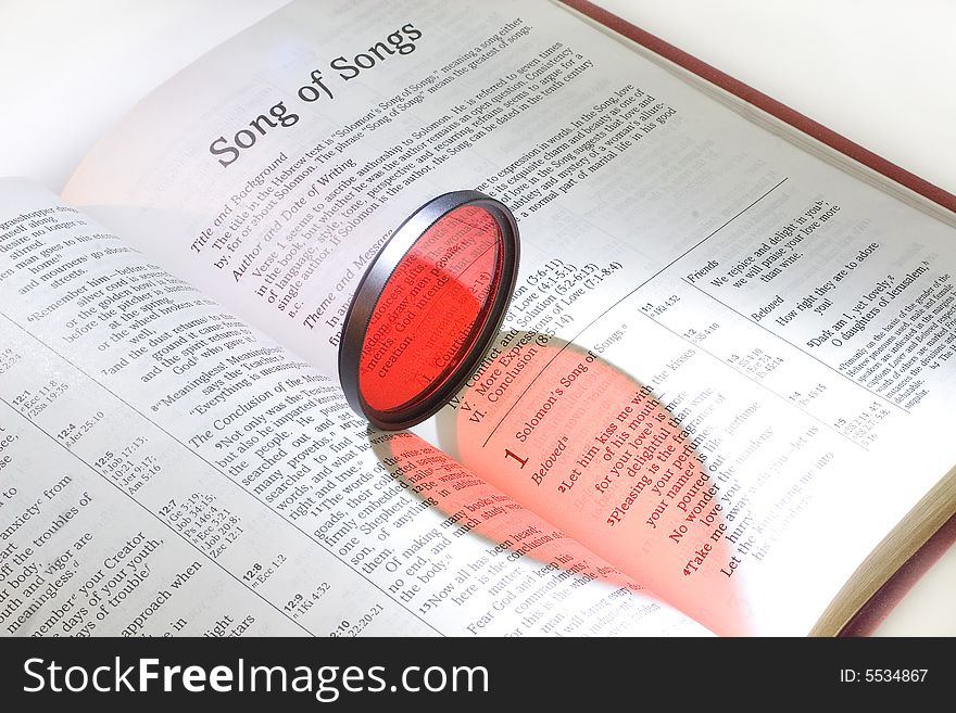 Holy Bible with a red heart (as a reflection of a red filter) on pages of the Song of Songs