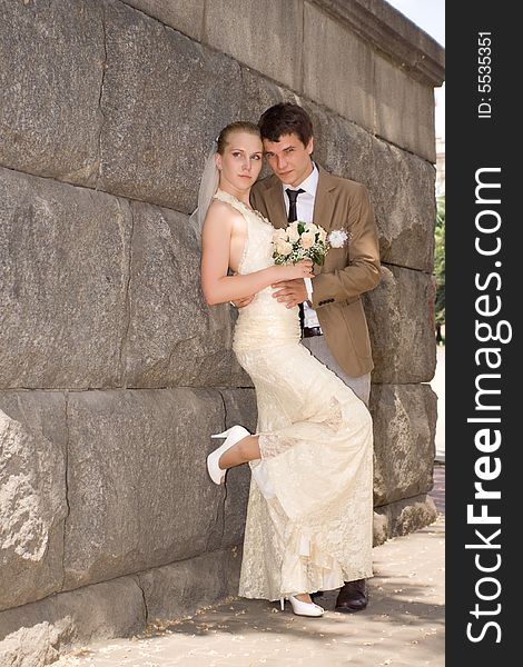 Newly-married couple near a stone wall