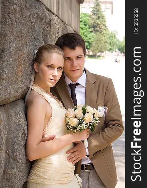 Newly-married couple near a stone wall