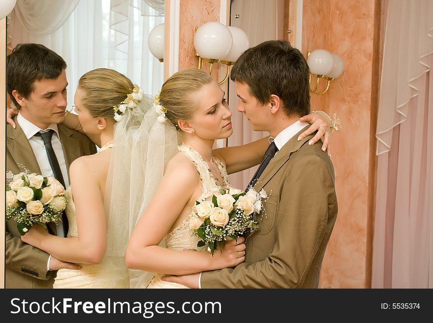 Newly-married couple embraces near a mirror