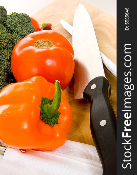 Assorted fresh vegetables on cutting board with chefs - cooks knife