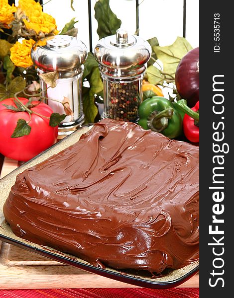 Plain iced chocolate cake in kitchen.