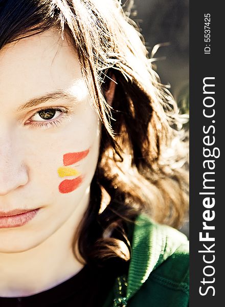 Sport fan with painted face, representing Spanish flag.