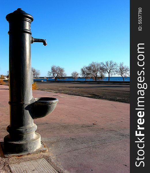 A small water fountain not working anymore on a pavement along the beach