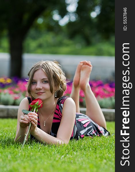 A Teenage girl relaxing at a park barefoot with a rose. A Teenage girl relaxing at a park barefoot with a rose