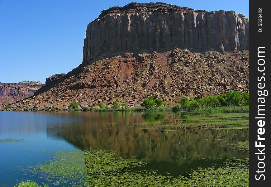 A sandstone mesa reflection in the waters of a small river, near Canyonlands National Park, Moab, Utah. A sandstone mesa reflection in the waters of a small river, near Canyonlands National Park, Moab, Utah.