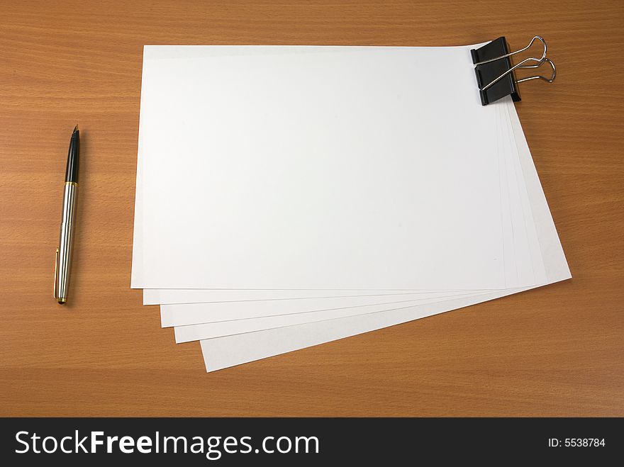 Blank papers and pen on wooden table surface. Blank papers and pen on wooden table surface.