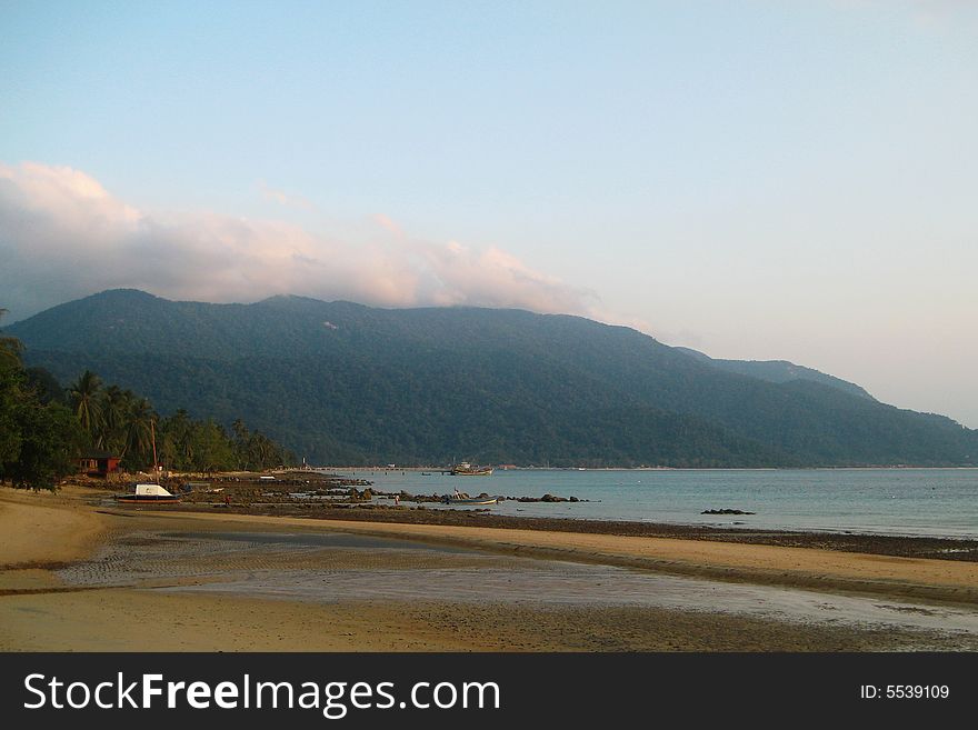 An island beach, a fishing village and a hill background. An island beach, a fishing village and a hill background