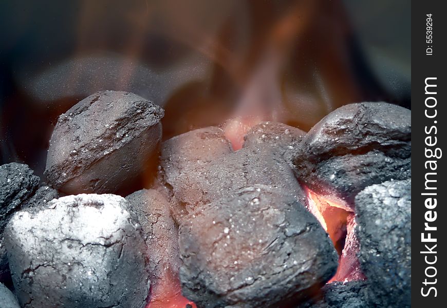 Close up view of smoldering charcoal  in flames for use in a barbecue grill. Close up view of smoldering charcoal  in flames for use in a barbecue grill.