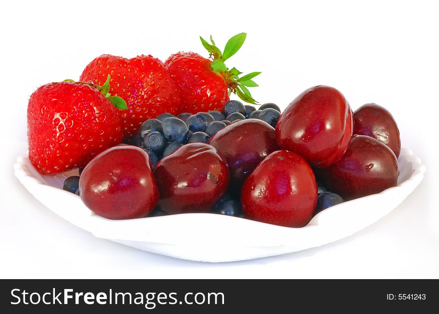 Fresh strawberries, bilberries and sweet cherry in white saucer. Fresh strawberries, bilberries and sweet cherry in white saucer