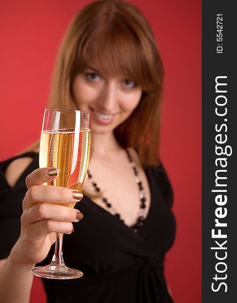 Girl with champagne, focus on glass isolated on red background