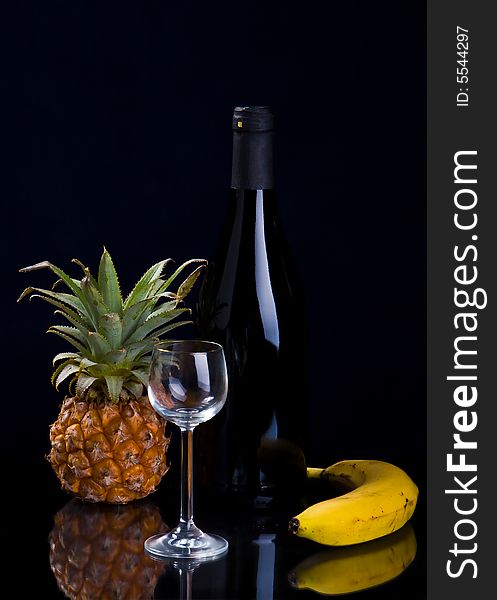 Fruit, a bottle and a glass on a black background. Fruit, a bottle and a glass on a black background