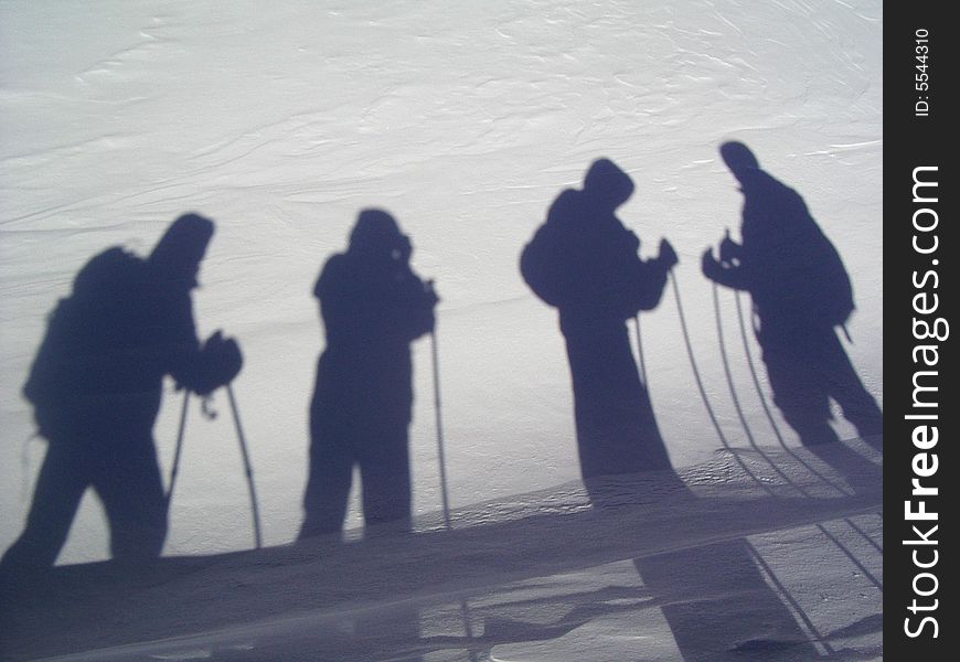 The person who photographes shadows of the friends on a snow in mountains. The person who photographes shadows of the friends on a snow in mountains.