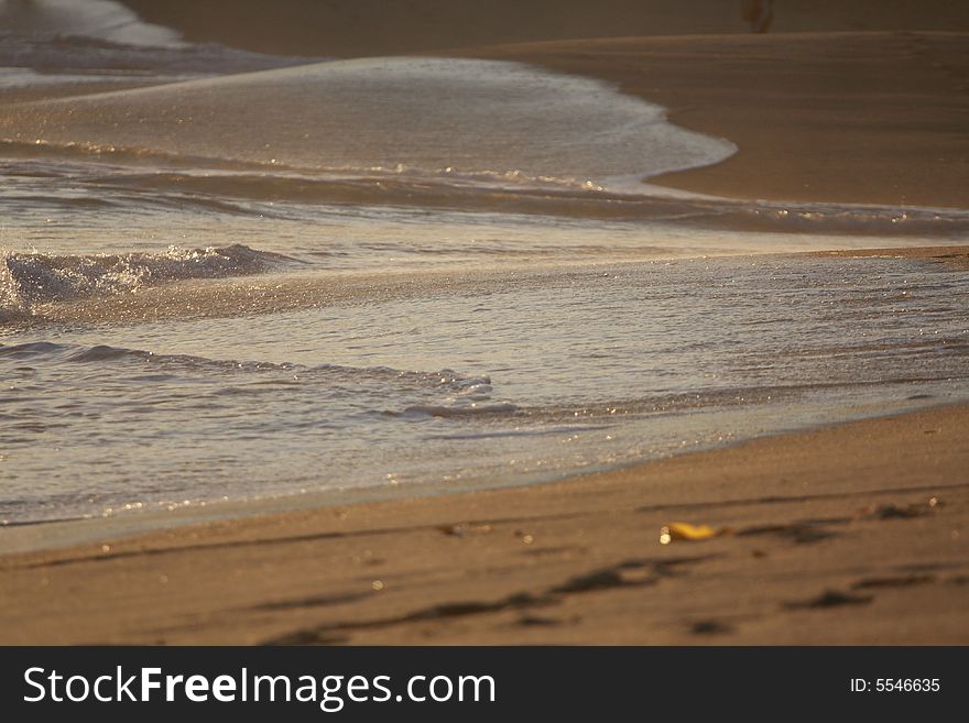 Small waves strike the surface of the sand at dusk. Small waves strike the surface of the sand at dusk.
