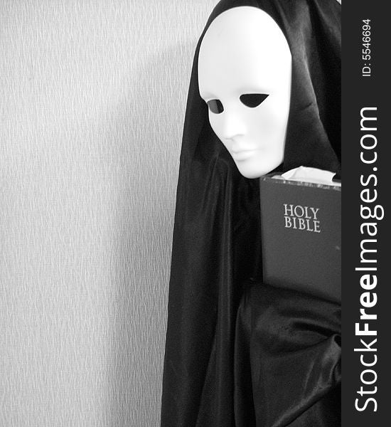 A black and white image of a masked image holding a bible. A black and white image of a masked image holding a bible.