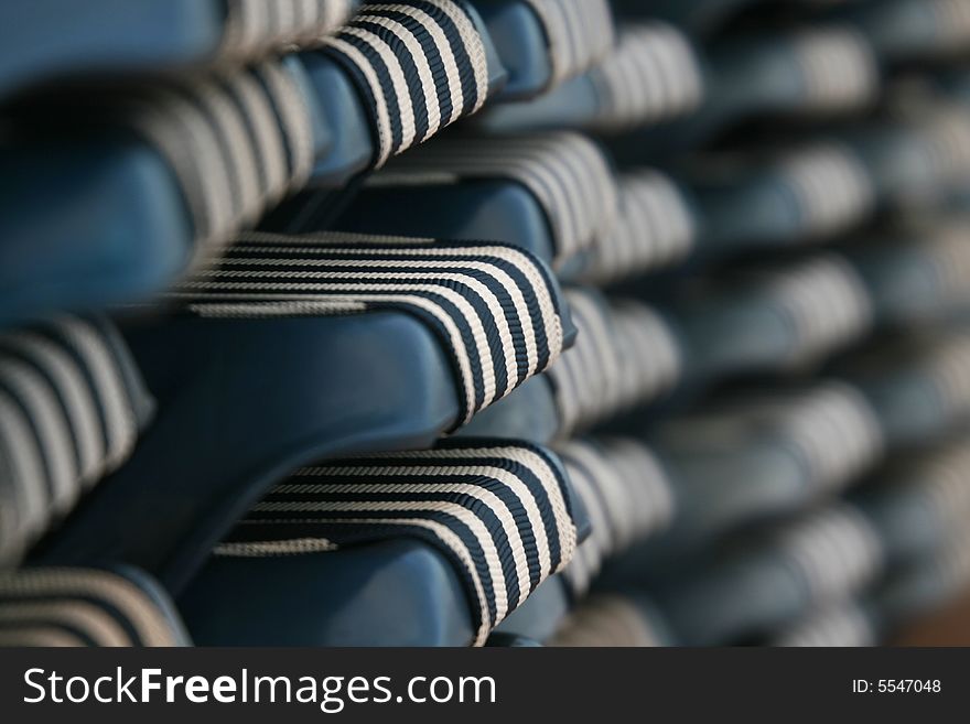 A close up of a group of striped beach chairs stacked for storage. A close up of a group of striped beach chairs stacked for storage.