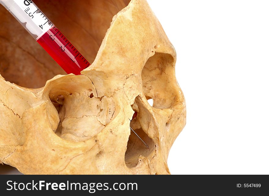 Old broken skull against white background with syringe with red liquid