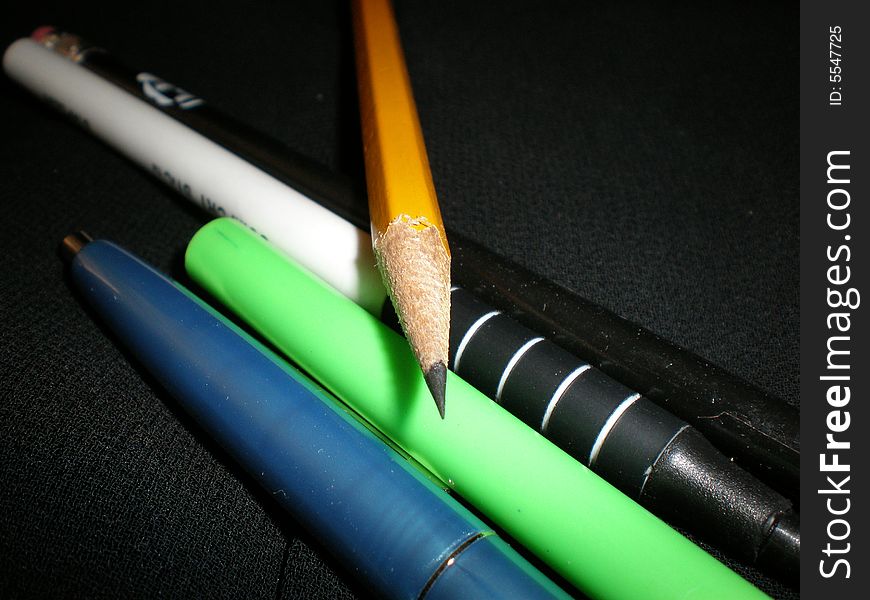 A few pens with a sharp pencil going across the pens. A few pens with a sharp pencil going across the pens.