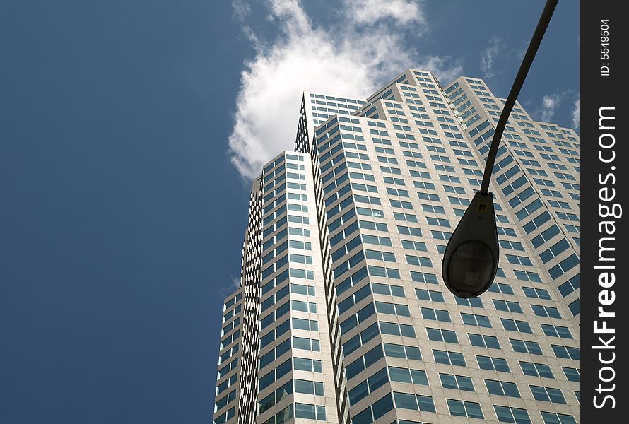 A tall office tower behind a lamp post in a view from the ground up. A tall office tower behind a lamp post in a view from the ground up.