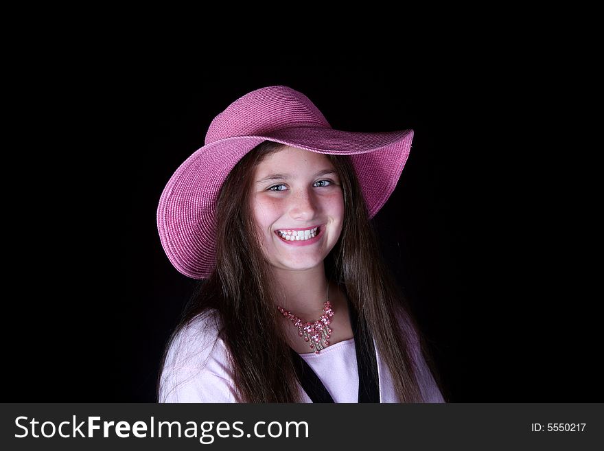 Young fashion model wearing a pink hat isolated on black background