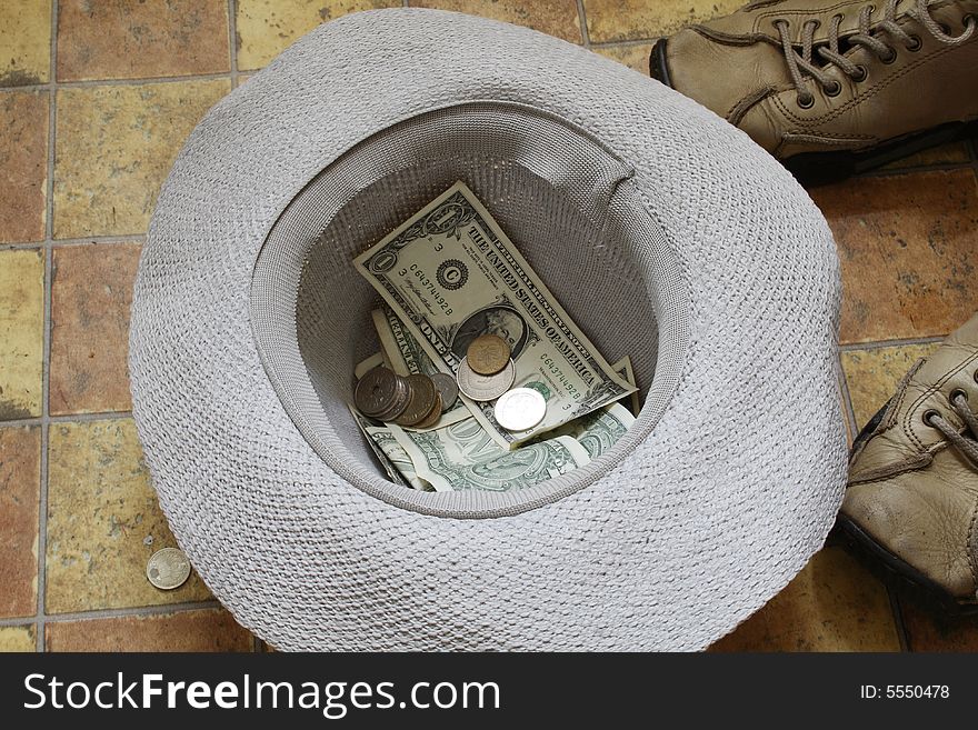 Beggar's hat with money lying on pavement