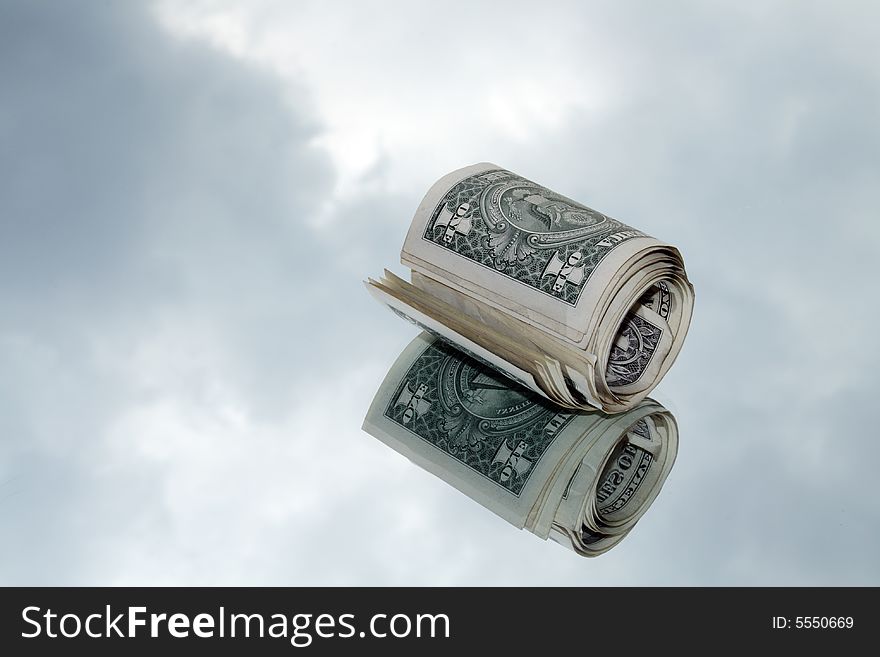 Little roll of one dollar banknotes on background with gray sky. Little roll of one dollar banknotes on background with gray sky