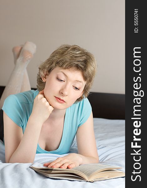 Young woman reading book on a bed, shallow DOF, focus on eyes. Young woman reading book on a bed, shallow DOF, focus on eyes