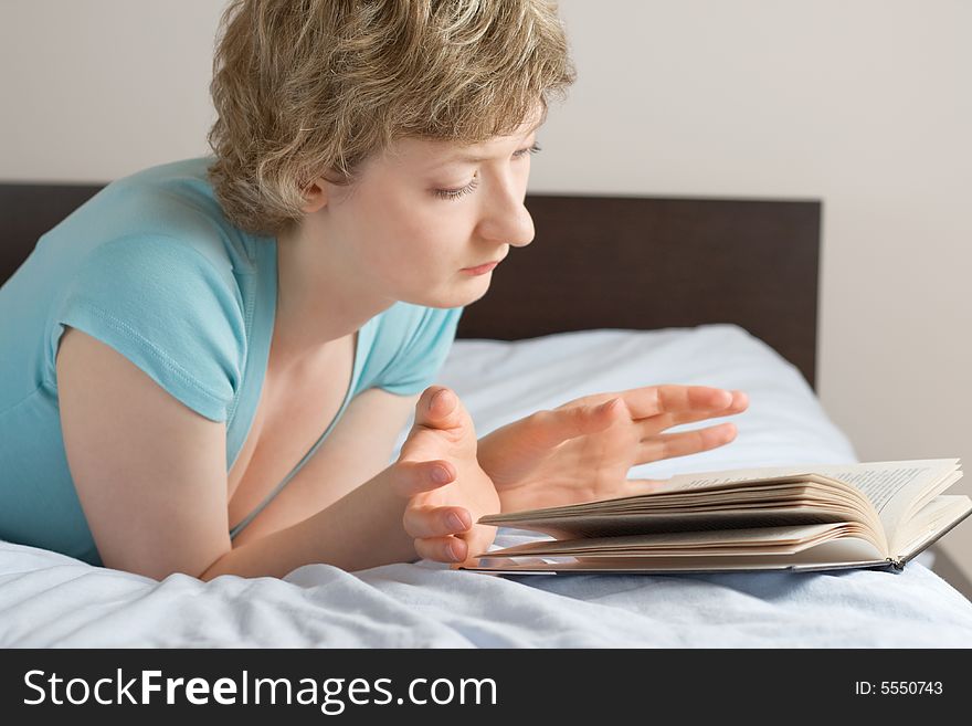 Young woman reading book on a bed, shallow DOF, focus on eyes. Young woman reading book on a bed, shallow DOF, focus on eyes