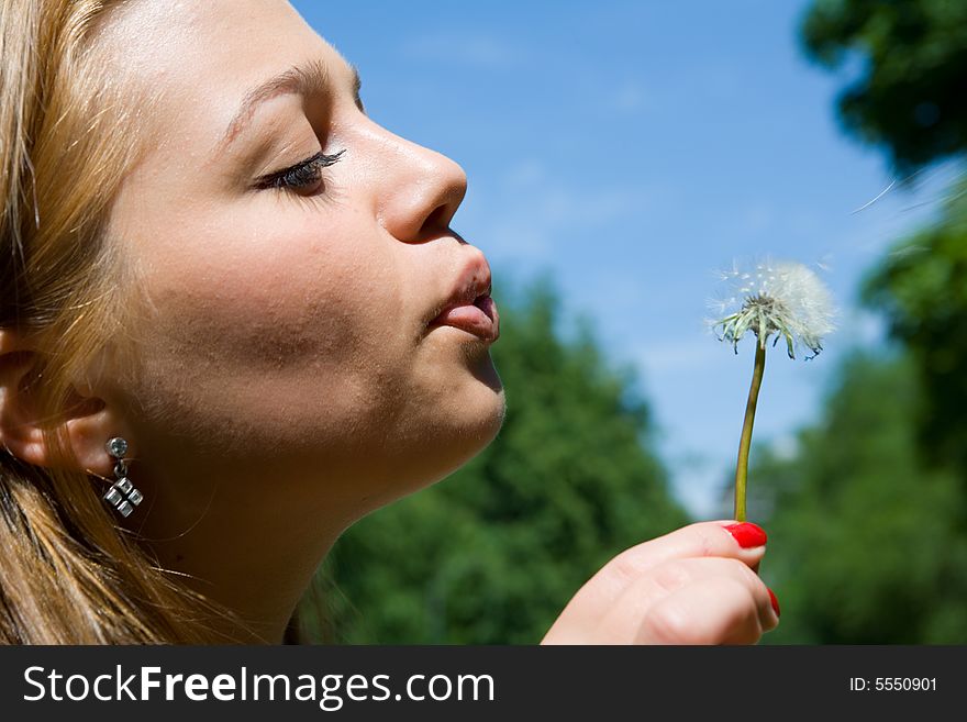 Beautiful young woman blowing dandelion. Beautiful young woman blowing dandelion