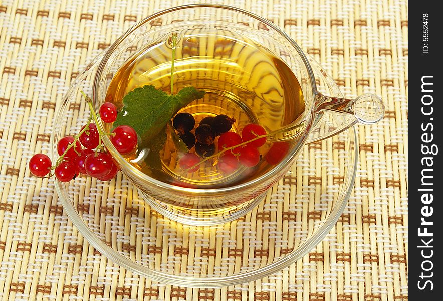 Red currant and herbal tea in a transparent cup