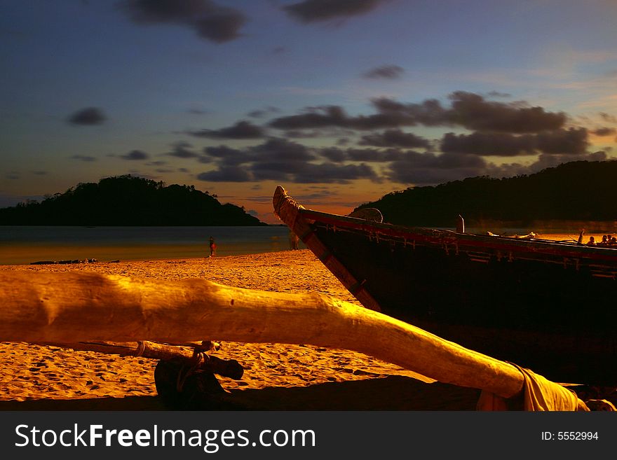 Beautiful sunset at a beach with a boat and wood in the foreground. Beautiful sunset at a beach with a boat and wood in the foreground.