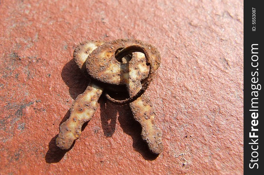 Two rusty old keys a ringlet laying on asphalt. Two rusty old keys a ringlet laying on asphalt