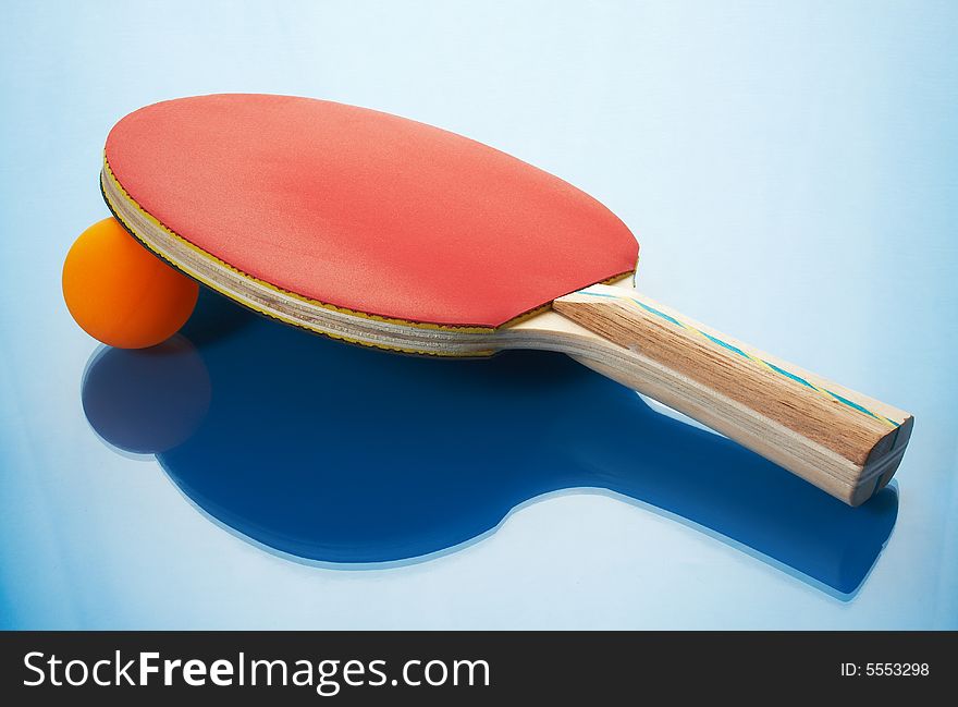 Tennis racket and orange ball on a blue background