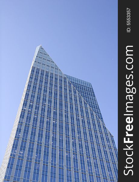 A modern blue office tower with a pointed top. A modern blue office tower with a pointed top