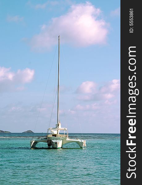 A Trimaran sailboat anchored in the bay of a paradise island setting. A Trimaran sailboat anchored in the bay of a paradise island setting.