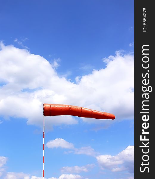 Red windsock detail. The blue sky with white clouds in the background.