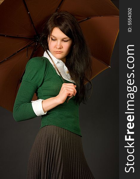 Serious looking girl in green sweater holding umbrella