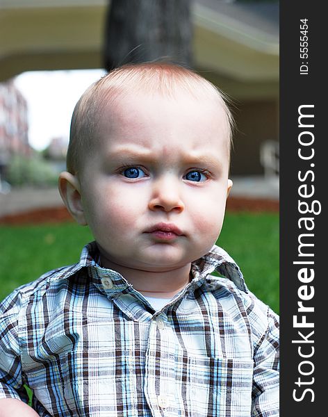 A young child gives off an intense, almost threatening, look at the camera in a park. - vertically framed. A young child gives off an intense, almost threatening, look at the camera in a park. - vertically framed