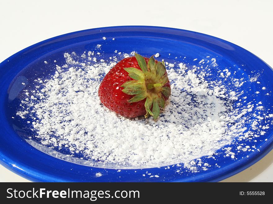 Single strawberry on blue plate with powdered sugar on white background. Single strawberry on blue plate with powdered sugar on white background