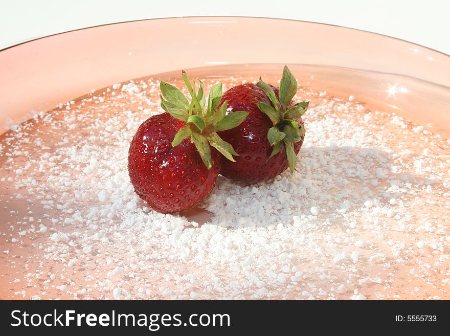 Single strawberry on pink plate with powdered sugar. Single strawberry on pink plate with powdered sugar