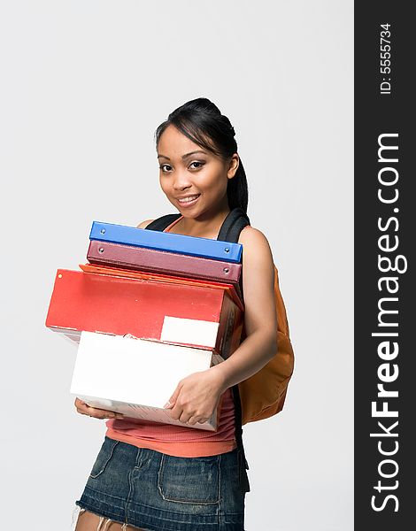 Overwhelmed female student wearing a backpack carries notebooks and papers. Vertically framed photograph. Overwhelmed female student wearing a backpack carries notebooks and papers. Vertically framed photograph.