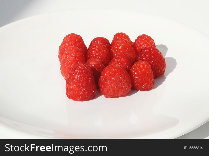 Many raspberries on white plate