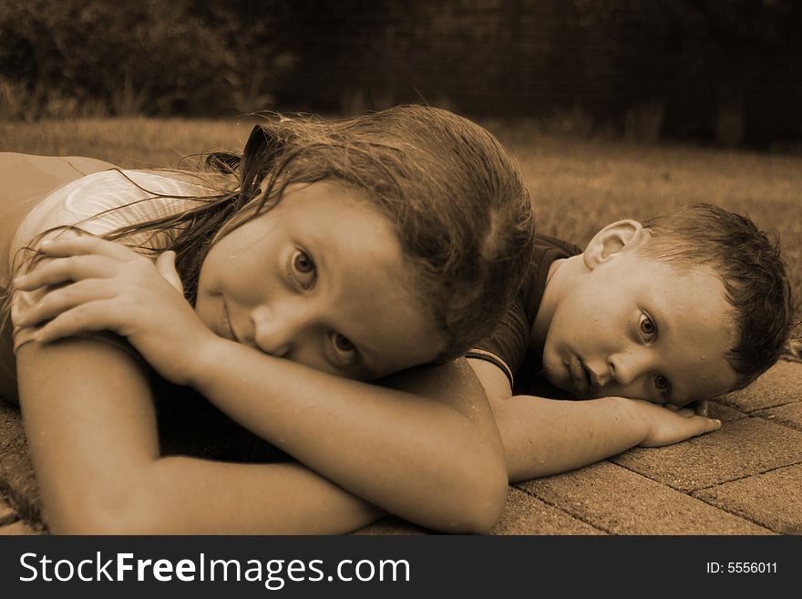 Sepia print of brother and sister lying outside together. Sepia print of brother and sister lying outside together.