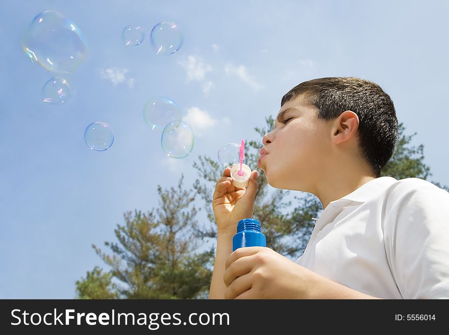 Young boy blowing bubbles in park. Copy space. Young boy blowing bubbles in park. Copy space