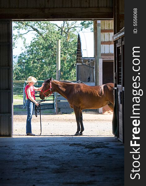 A trainer petting a horse outside of a horse stall - vertically framed. A trainer petting a horse outside of a horse stall - vertically framed