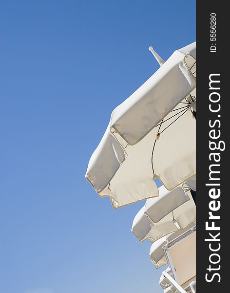 Line of sun white sun umbrellas on a clean blue sky