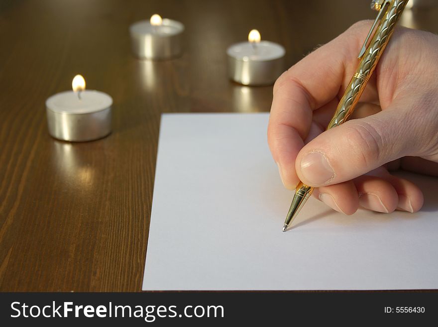 Hand wiriting with golden pen with candles. Hand wiriting with golden pen with candles