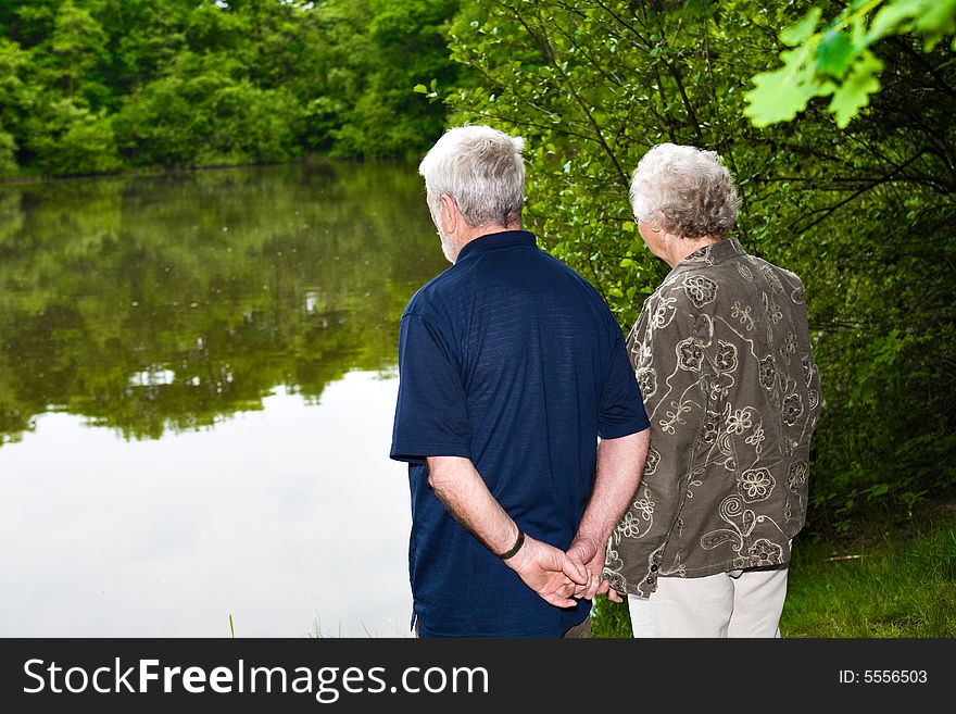 Outside portrait of an elderly couple standing near a lake. Outside portrait of an elderly couple standing near a lake