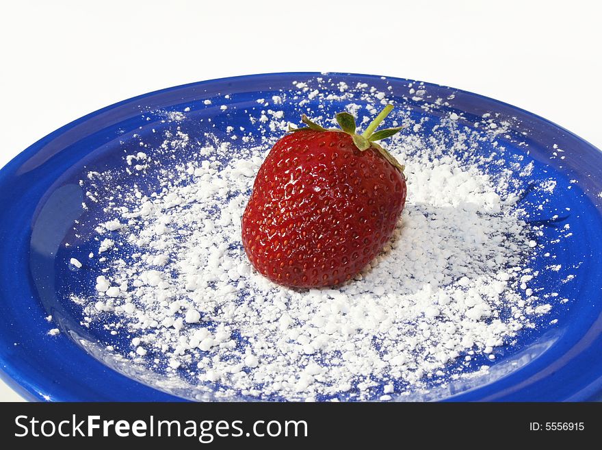 Single strawberry on blue plate with powdered sugar on white. Single strawberry on blue plate with powdered sugar on white